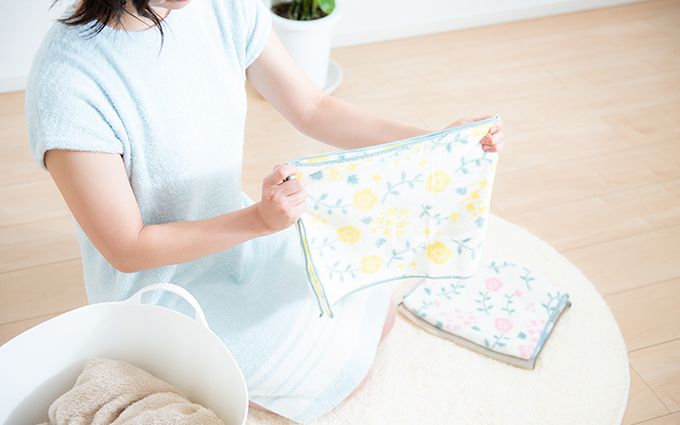 洗濯物をたたむ女性の画像