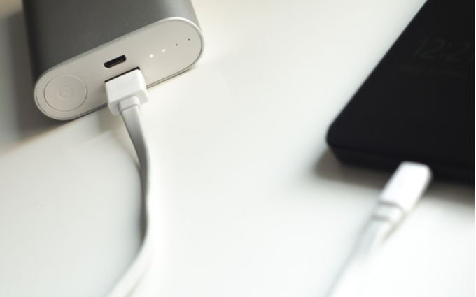シルバーのモバイルバッテリーとiPhoneの画像