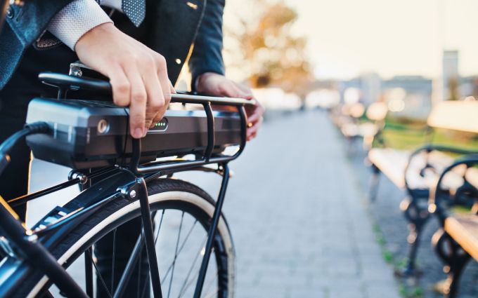 通勤中の人が電動自転車のバッテリーを触っている画像