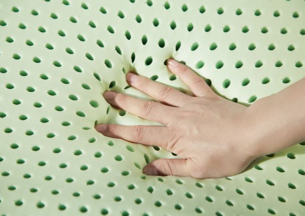 空気を通すラテックスのマットレスを手で押している画像