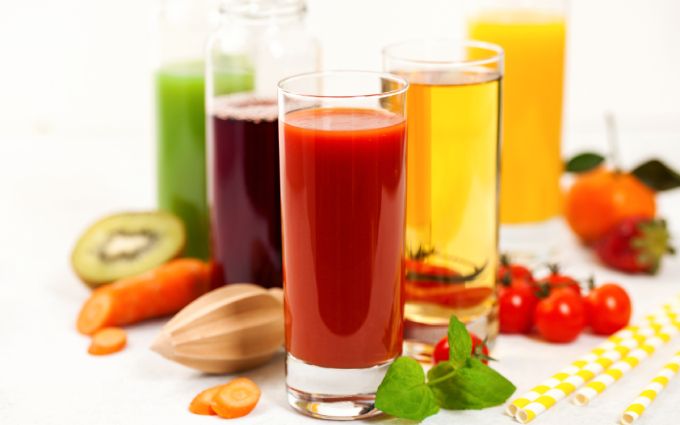 グラスに入った複数の酵素ドリンクと野菜や果物が散らばっている画像