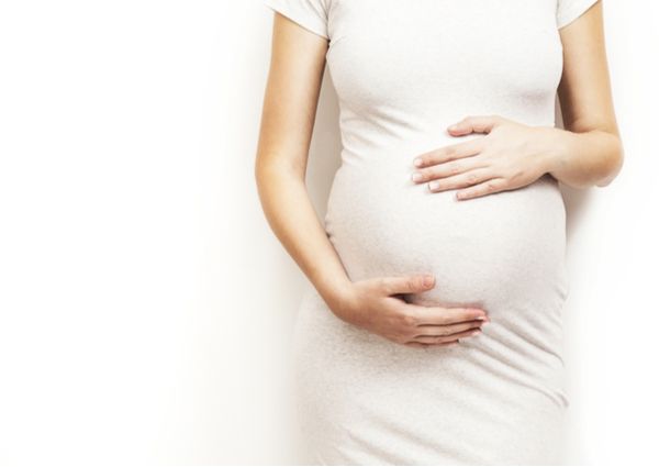 妊婦が大きなお腹に手を添えている画像