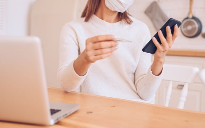 スマートフォンと連携できる体温計を持っている女性の画像