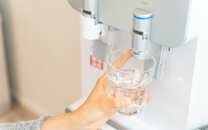 ウォーターサーバーの水をグラスに入れている人の画像