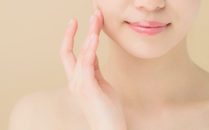 頬を指で触る女性の画像