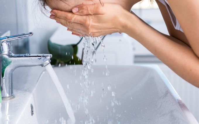 水で顔を洗っている女性の画像