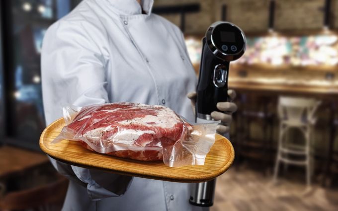 低温調理器とこれから調理する肉を持つ女性の画像