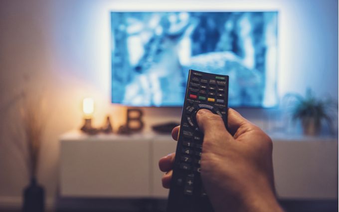 テレビ画面に向けてリモコンのボタンを押している手のアップ画像