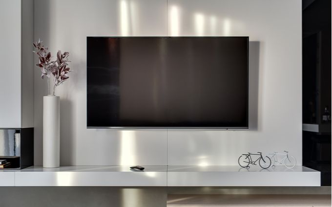 大型の80インチテレビが壁掛け設置されている画像