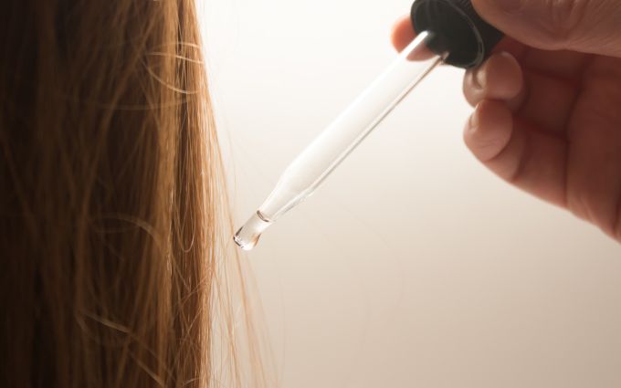 女性の髪の毛に育央剤をつけようとしている画像