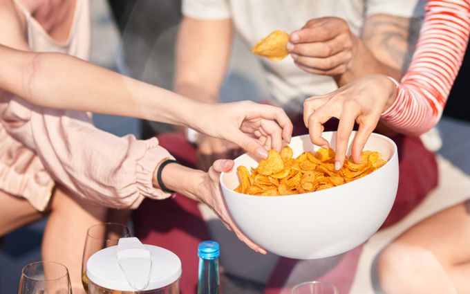複数人でお皿に入ったポテトチップスをつまむ画像