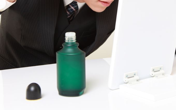 髪に育毛剤をつけている男性の画像